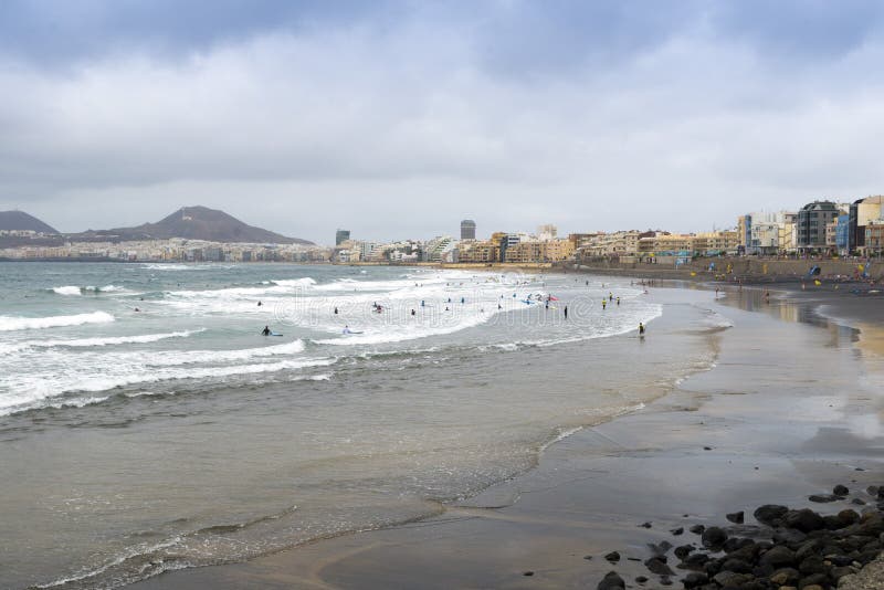 LAS PALMAS DE GRAN CANARIA, SPAIN - AUGUST 3, 2016: swimmers and surfers on the beach Las Canteras in Las Palmas, Canary Islands. LAS PALMAS DE GRAN CANARIA, SPAIN - AUGUST 3, 2016: swimmers and surfers on the beach Las Canteras in Las Palmas, Canary Islands