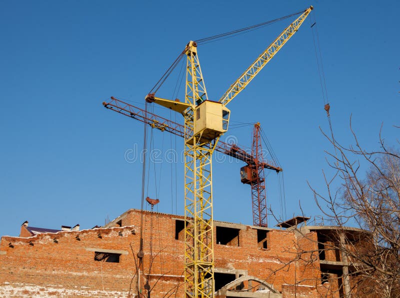 Cantiere di alta costruzione del nuovo appartamento con le gru a torre contro cielo blu Sviluppo di zona residenziale Bene immobi fotografia stock libera da diritti Cantiere di alta costruzione del nuovo appartamento con le gru a torre contro cielo blu Sviluppo di zona residenziale Bene immobi fotografia stock libera da diritti