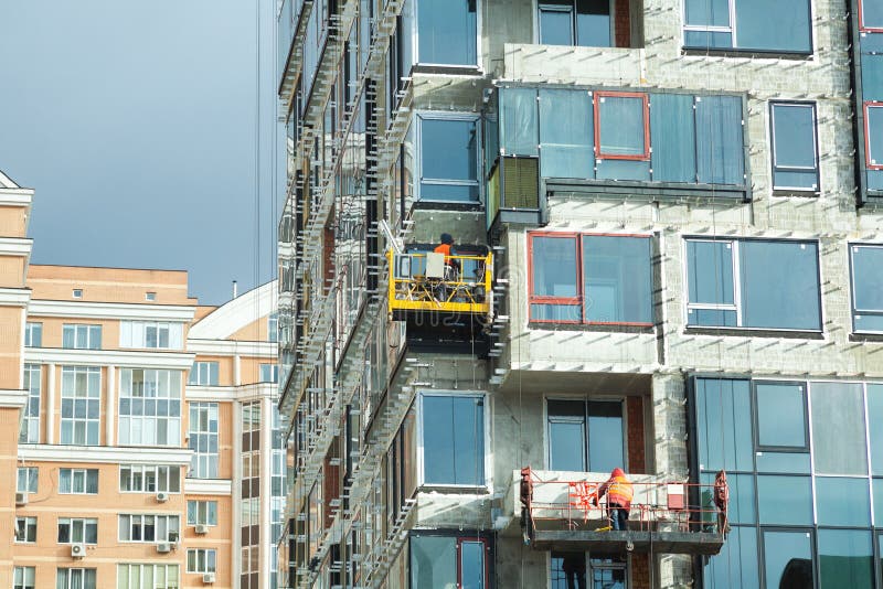 Cantiere grande d'esame I lavoratori che costruiscono la nuova casa, installano Windows, isolamento della parete, balcone Fabbric fotografia stock libera da diritti Cantiere grande d'esame I lavoratori che costruiscono la nuova casa, installano Windows, isolamento della parete, balcone Fabbric fotografia stock libera da diritti