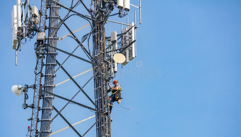 Canton, Ohio lake, USA. May 8, 2019. Communication maintenance. Technician climbing on telecom tower antenna against blue sky background, copy space. Canton, Ohio lake, USA. May 8, 2019. Communication maintenance. Technician climbing on telecom tower antenna against blue sky background, copy space