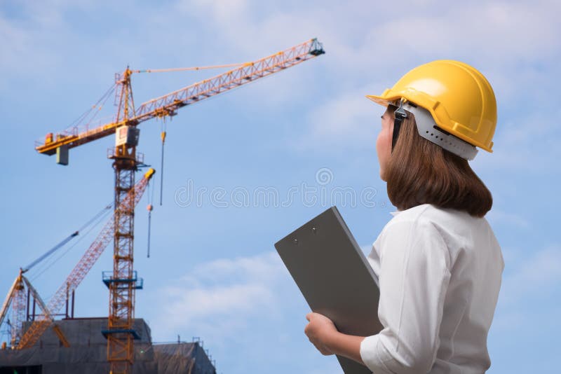 Capacete de segurança vestindo do coordenador fêmea no canteiro de obras imagem de stock Capacete de segurança vestindo do coordenador fêmea no canteiro de obras imagem de stock