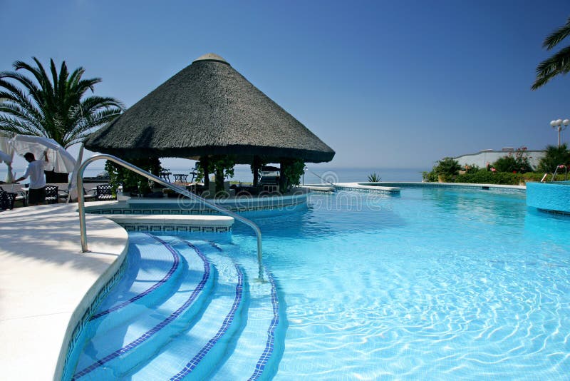 Capanna e barra di Tiki dalla piscina dell'albergo di lusso fotografia stock
