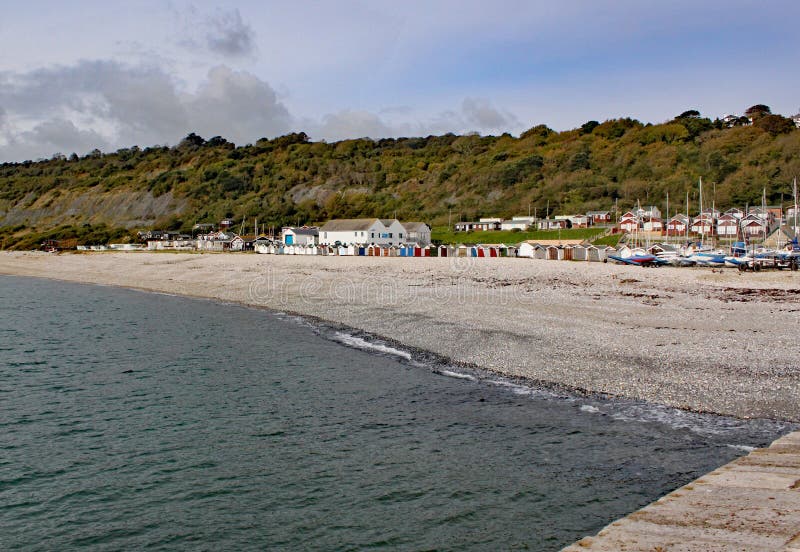 Capanne della spiaggia sulla spiaggia dell'assicella osservata dal Cobb a Lyme Regis, Dorset, Inghilterra immagini stock libere da diritti Capanne della spiaggia sulla spiaggia dell'assicella osservata dal Cobb a Lyme Regis, Dorset, Inghilterra immagini stock libere da diritti