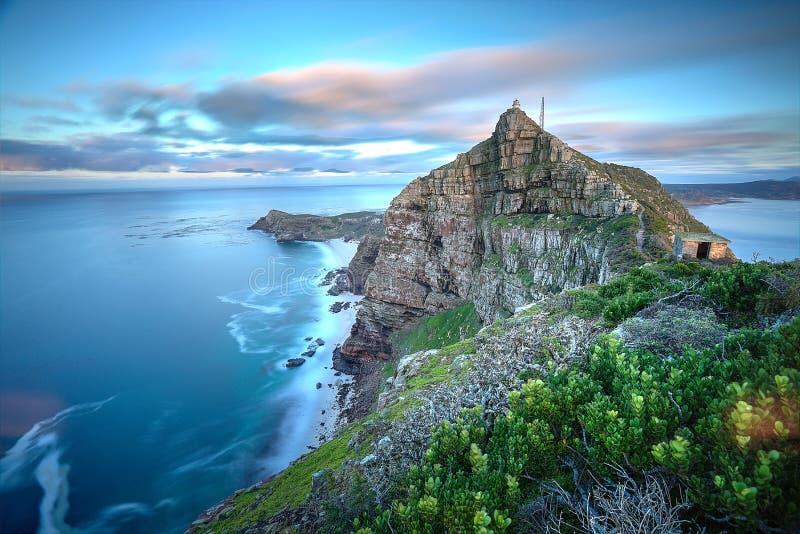 La punta del capo, Sud Africa, come il tempo si ferma un leggero movimento in acqua e nuvole, come il sole sorge nella parte posteriore.