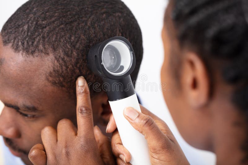 Capelli del dottore Examining Man con Dermatoscope fotografie stock Capelli del dottore Examining Man con Dermatoscope fotografie stock