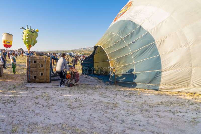 Cappadocia/Turchia - 7 luglio 2019: La squadra al tramonto prepara la mongolfiera per il volo Assemblea e riempire il pallone fotografie stock Cappadocia/Turchia - 7 luglio 2019: La squadra al tramonto prepara la mongolfiera per il volo Assemblea e riempire il pallone fotografie stock