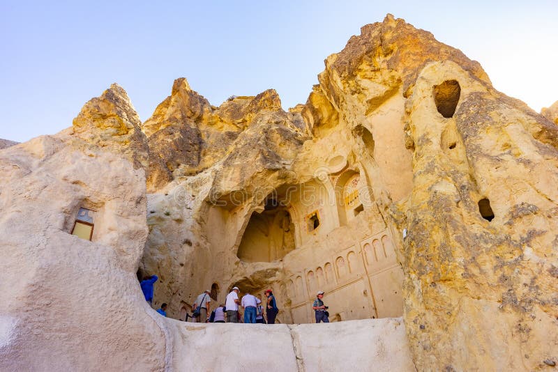 Cappadocia, Turquia, o 13 de setembro de 2018: Turistas que olham a igreja antiga, o monastério o maior do rocha-corte de imagem de stock Cappadocia, Turquia, o 13 de setembro de 2018: Turistas que olham a igreja antiga, o monastério o maior do rocha-corte de imagem de stock