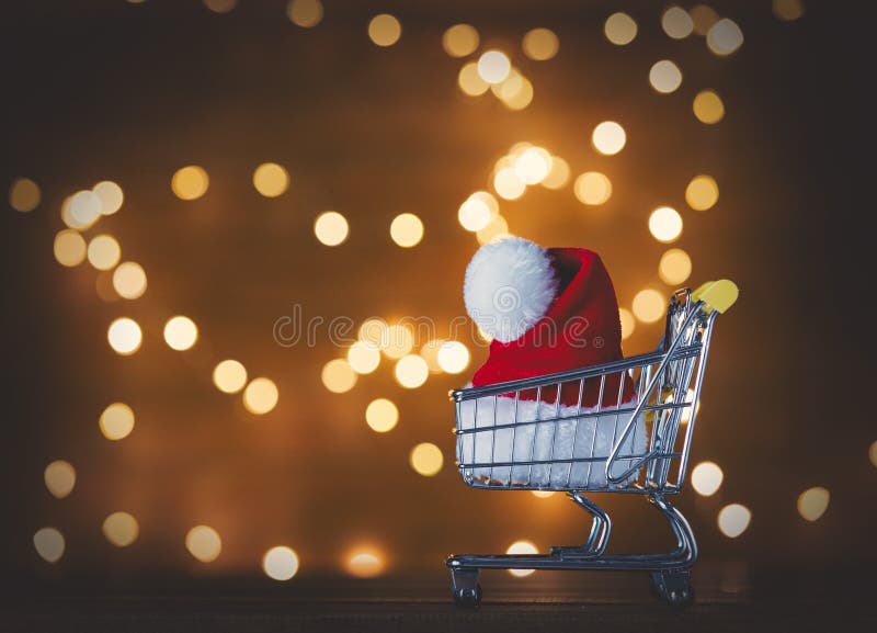 Cappello di Santa Claus in carrello e nelle luci di Natale immagini stock libere da diritti Cappello di Santa Claus in carrello e nelle luci di Natale immagini stock libere da diritti