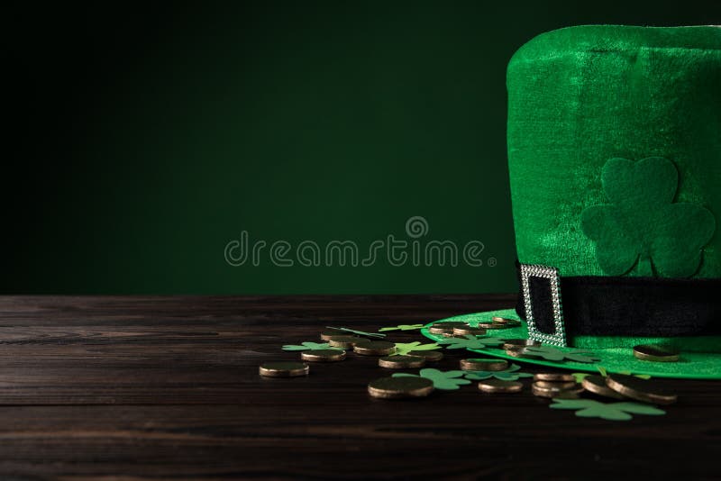 Cappello verde con le monete dorate ed acetosella sulla tavola di legno fotografia stock Cappello verde con le monete dorate ed acetosella sulla tavola di legno fotografia stock