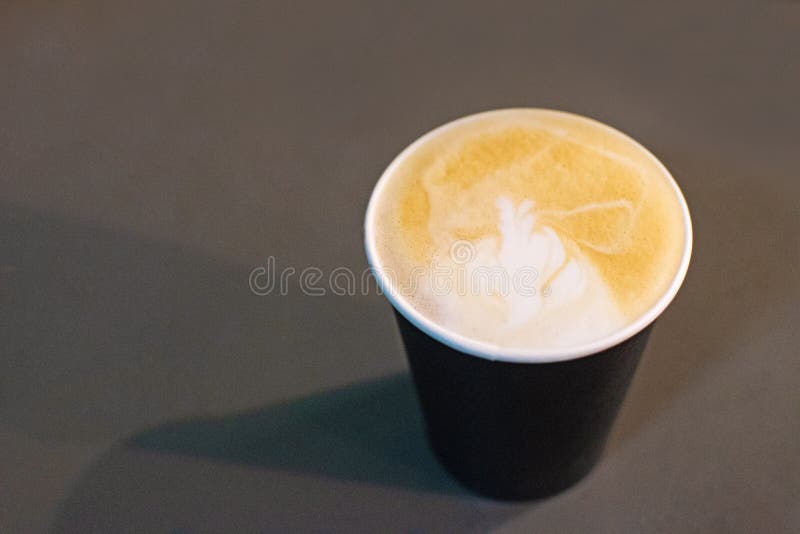 Cappuccino-cupen med ett mönster på skummet på grå bakgrund royaltyfri fotografi Cappuccino-cupen med ett mönster på skummet på grå bakgrund royaltyfri fotografi