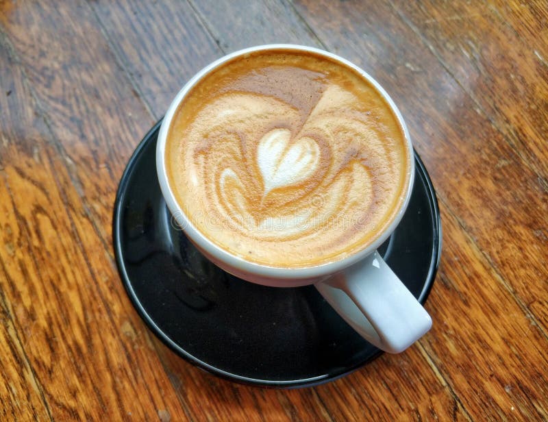Cappuccino hjärtkaffekonst på mörk träbakgrund fotografering för bildbyråer