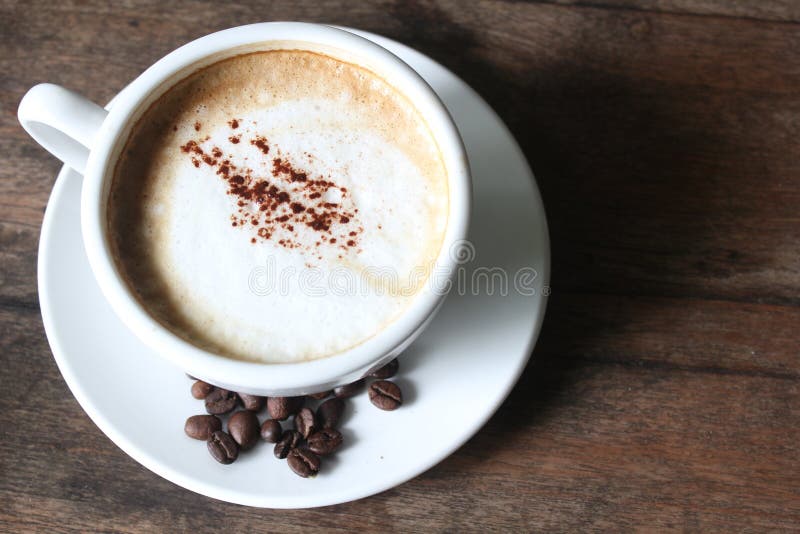 Cappuccino with milk froth and coffee beans. Cappuccino with milk froth and coffee beans on the old wooden desk as background stock photos Cappuccino with milk froth and coffee beans. Cappuccino with milk froth and coffee beans on the old wooden desk as background stock photos