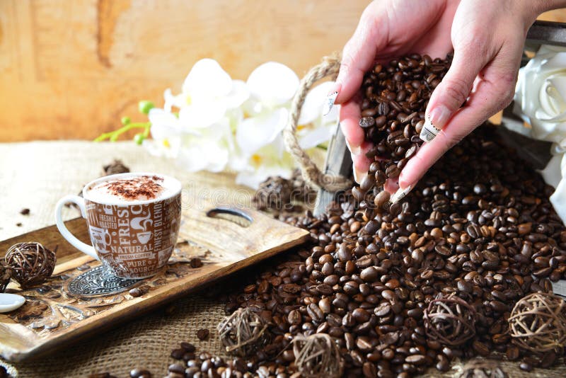 Cappuccinohand mit fallenden Bohnen lizenzfreie stockbilder Cappuccinohand mit fallenden Bohnen lizenzfreie stockbilder