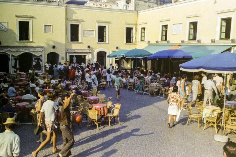 CAPRI, ITALY, 1965 - The sun sets on the coffee tables and on passers-by in the famous Piazzetta of Capri