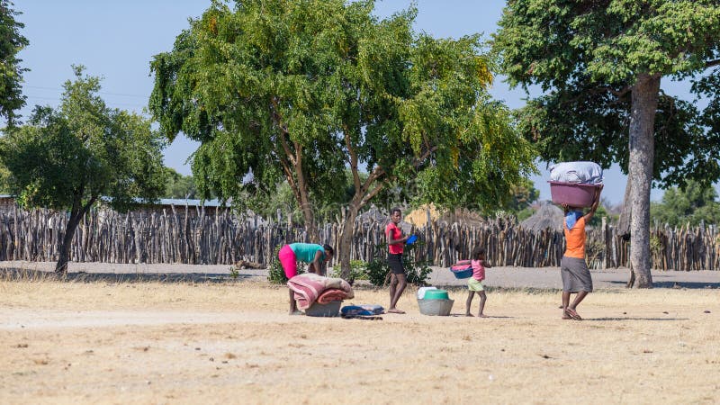 Caprivi, Namibia - August 20, 2016: Poor women walking on the roadside in the rural Caprivi Strip, the most populated region in Namibia, Africa. Caprivi, Namibia - August 20, 2016: Poor women walking on the roadside in the rural Caprivi Strip, the most populated region in Namibia, Africa.