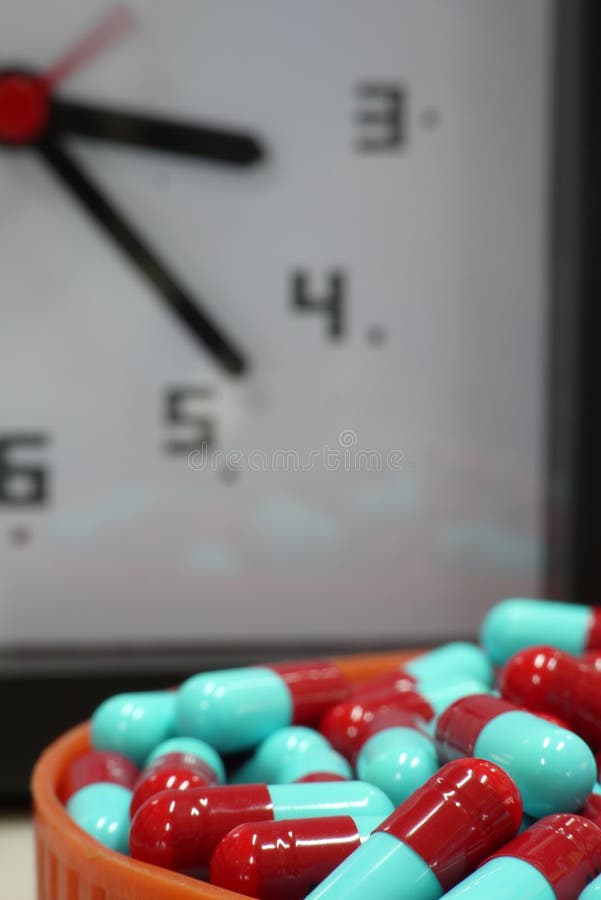 Capsule rouge et bleue avec le fond d'horloge images libres de droits Capsule rouge et bleue avec le fond d'horloge images libres de droits