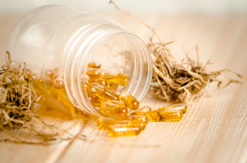 Capsules of Fish Oil Spilled Out Open Container. Shot in Studio on