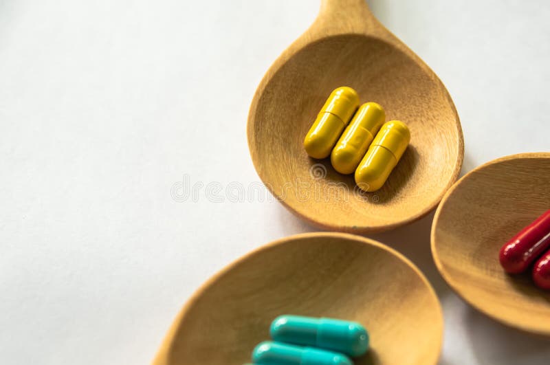 Capsules of Thai herbs medicine in the wooden spoon on white background, tropical herb ,organic plants for health care concept.
