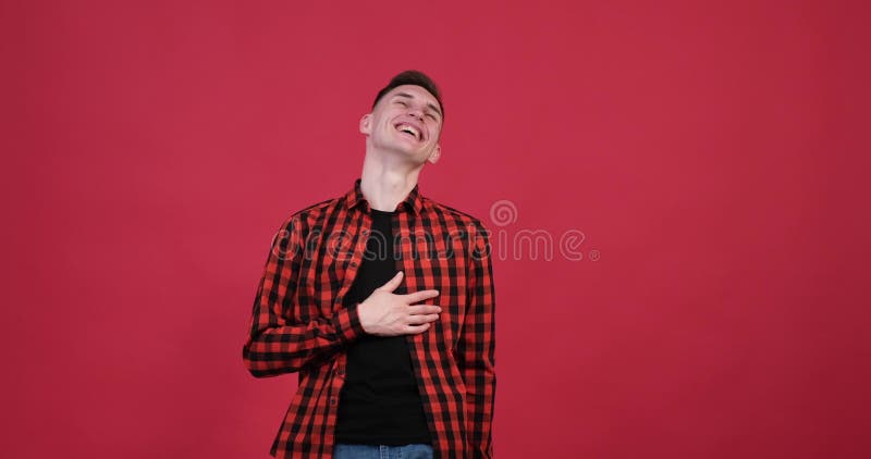 Bărbat caucazian care râde și se uită la cameră pe fundal roșu stock video