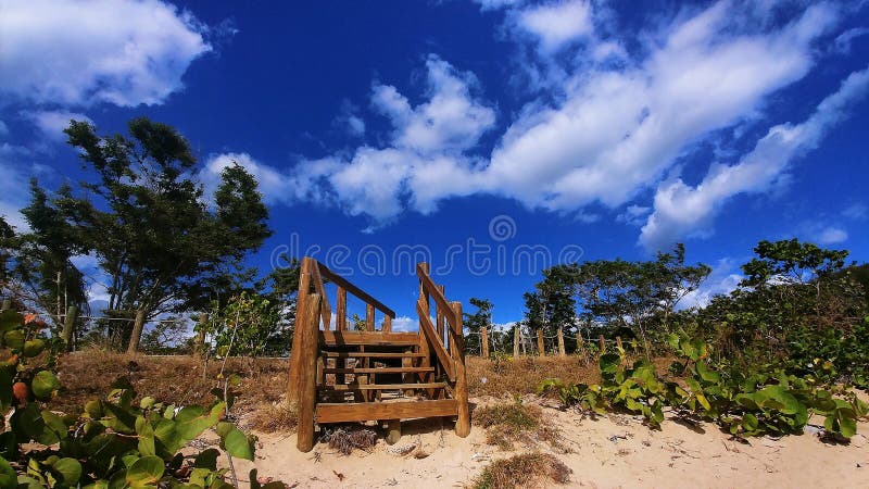 In this captivating scene, sand and stairs converge at the shore, creating a seamless blend with the sky above. The stairs, seemingly a path to infinity, invite onlookers into a realm where earth and heaven merge. With every grain of sand glowing under the ethereal light, this image captures a moment of sublime tranquility, where time stands still and the beauty of nature speaks in silent whispers. Captivating path stock images, royalty-free photos and pictures