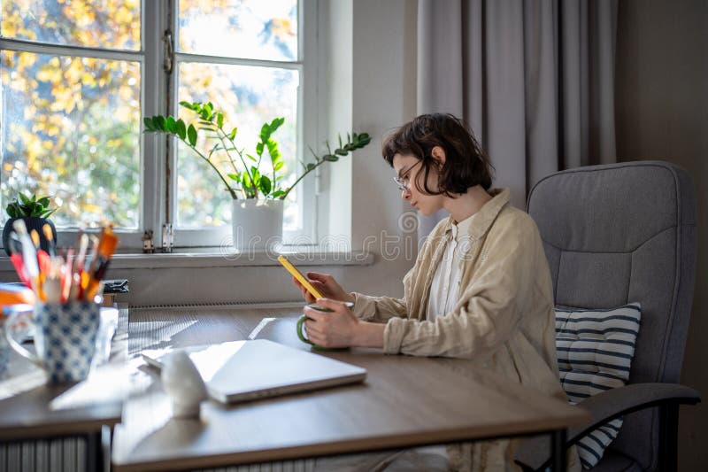 Captivé par la jeune fille du téléphone portable qui défilent sur les médias sociaux qui discutent assis au bureau prendre une pau images libres de droits