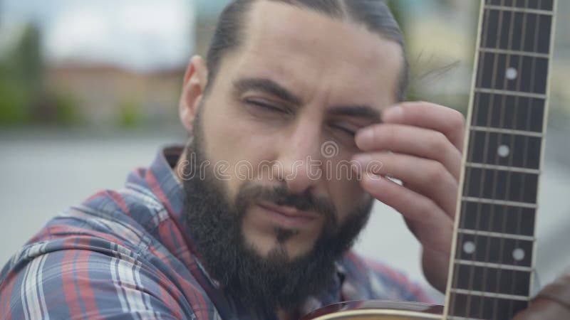 Captura de cabeça de um músico bonito com o teclado do violão Retrato detalhado do pensado homem-morena com barba caucasiana