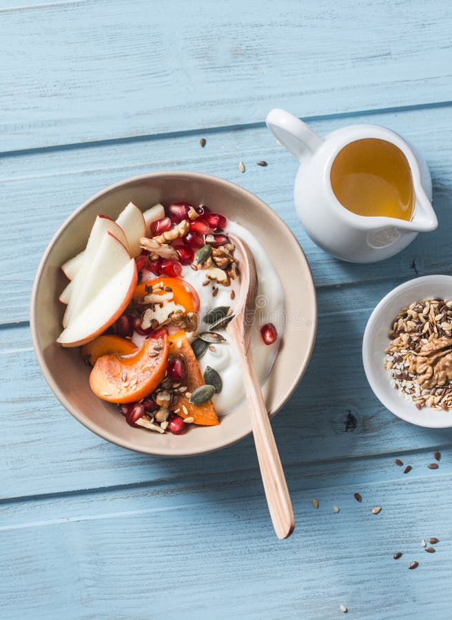 Caqui, manzana, nueces, granadas, semillas y yogur natural Concepto sano de la comida en el fondo azul, visión superior Fruta y G fotos de archivo Caqui, manzana, nueces, granadas, semillas y yogur natural Concepto sano de la comida en el fondo azul, visión superior Fruta y G fotos de archivo
