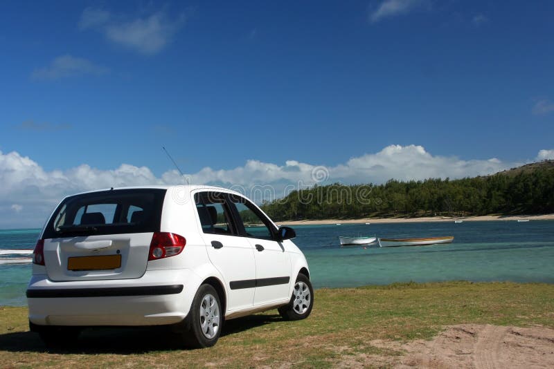 Bianco di una piccola automobile di erba verde, sulla spiaggia.