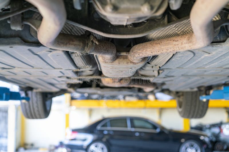 Car bottom view double or two exhaust suspension pipe system of saloon or sedan car at garage lift up for maintenance stock photography Car bottom view double or two exhaust suspension pipe system of saloon or sedan car at garage lift up for maintenance stock photography