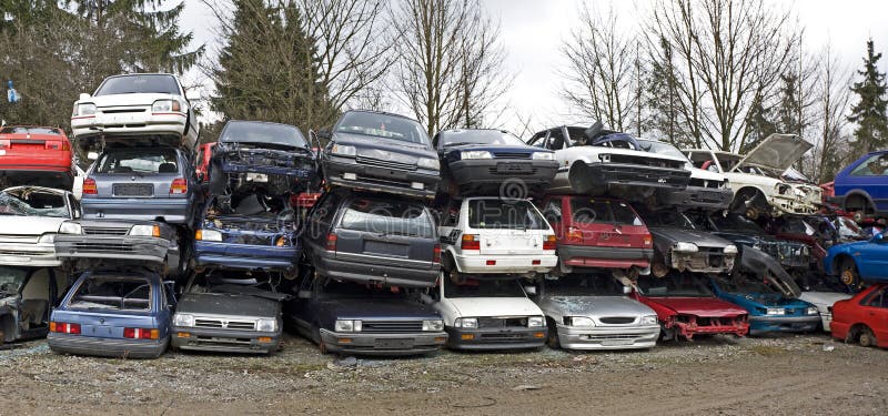 Wrecked cars stacked in an outdoor scrap yard.