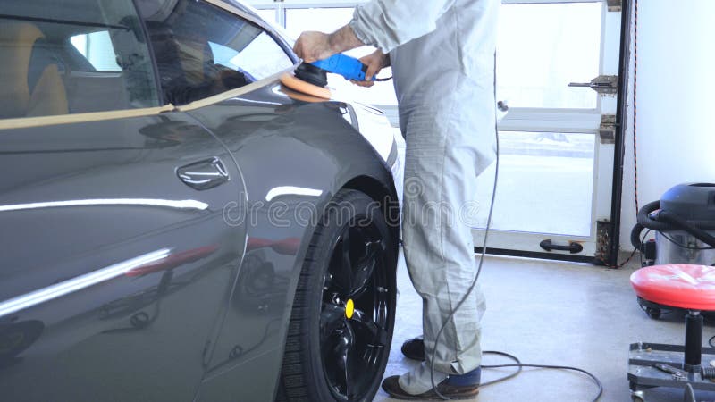 In the car center in the garage, professionals polish a new sports car. Luxury car polishing. Concept of: Racing, Sport car, New, Slow motion, Nascar, Red, Chrome plated.