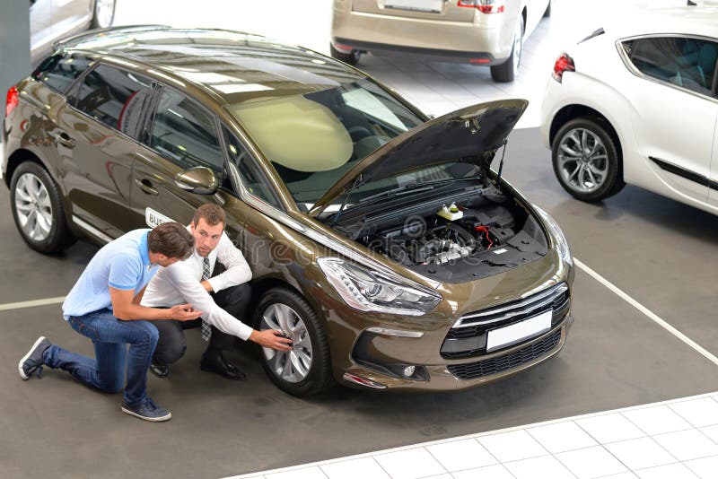 Car dealership advice - sellers and customers when buying a car - technology talk about the tires royalty free stock image Car dealership advice - sellers and customers when buying a car - technology talk about the tires royalty free stock image