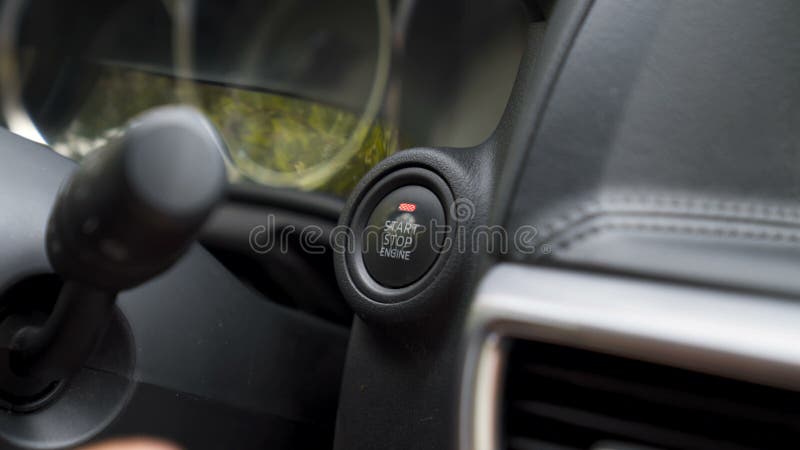 Car driver pressing a button and starting the engine