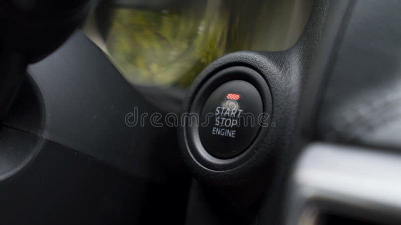 Car driver pressing a button and starting the engine