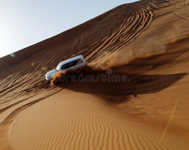 Car driving down sand dune stock photography