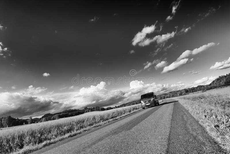 Car, suv, driving along on a lonely narrow country-road, summer, green fields and meadows. monochromatic tint. sweden. Car, suv, driving along on a lonely narrow country-road, summer, green fields and meadows. monochromatic tint. sweden