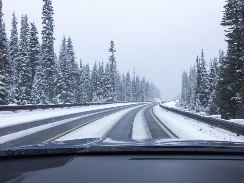 Car driving on snow-covered snowy mountain road in winter snow. Driver`s point of view viewpoint looking through windshield.