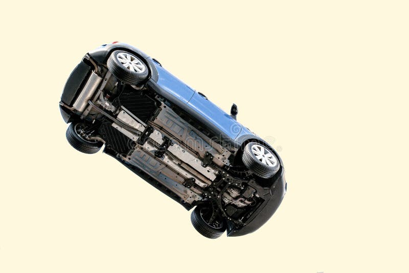 A car flying through the air in the pale blue sky with the underside including, wheels, engine and exhaust pipe visible