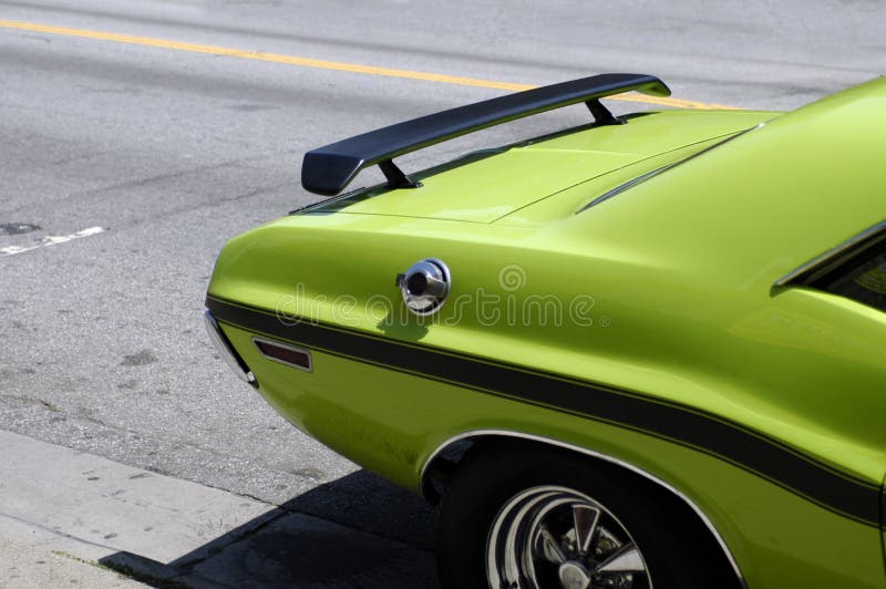 The rear fender and wheel of a green seventies American muscle car with a black body stripe. The rear fender and wheel of a green seventies American muscle car with a black body stripe