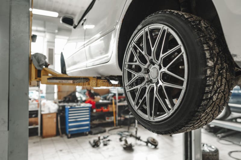 Car on a Hoist in Repair with Focus on the Wheel Stock Image