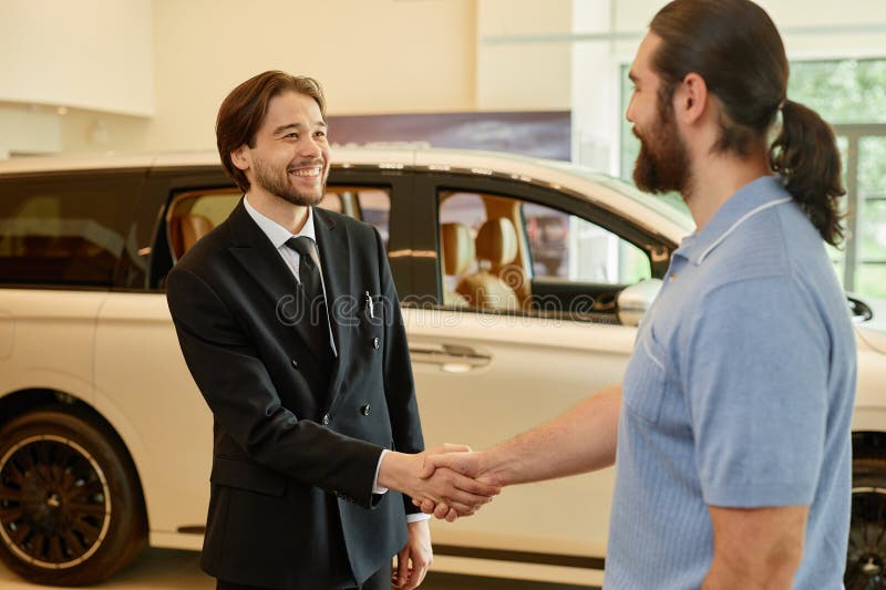 Car Manager Shaking Hands with Male Buyer at Dealership Center stock photo