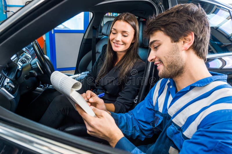 Car Mechanic With Customer Going Through Maintenance Checklist. Car mechanic with female customer going through maintenance checklist in automobile shop stock image Car Mechanic With Customer Going Through Maintenance Checklist. Car mechanic with female customer going through maintenance checklist in automobile shop stock image