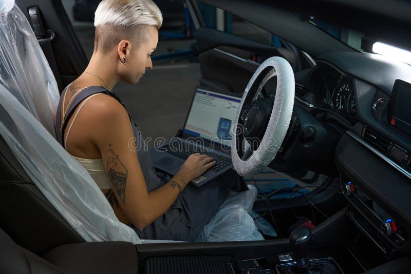 Car Mechanic in Work Overalls Conducts Computer Diagnostics of Car