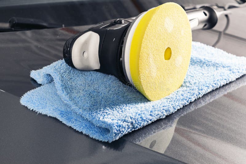 Car polish concept. Buffing and polishing car. Car detailing. Polisher and microfiber cloth on the car. Tools for polishing.