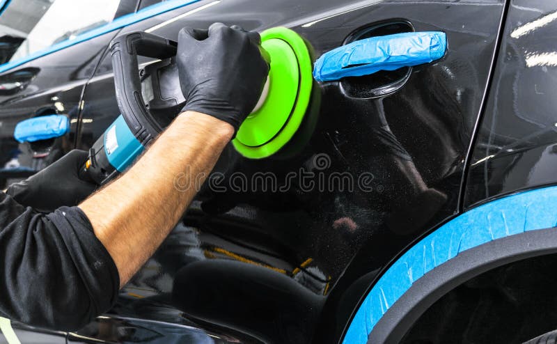 Car polish wax worker hands applying protective tape before polishing. Buffing and polishing car. Car detailing. Man holds a polis