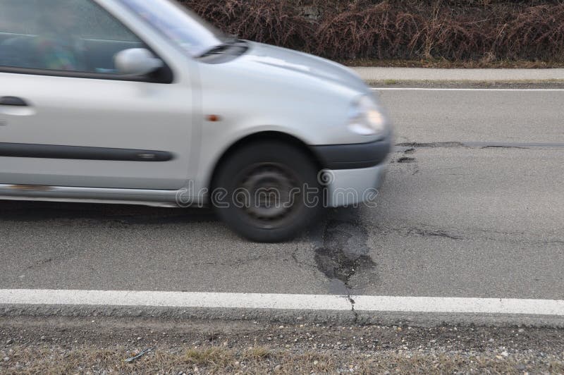 Car and pothole on road