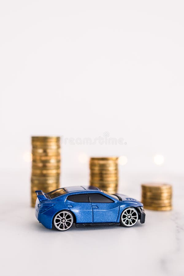 Car prices going down, toy car in fron of decreasing stacks of coins stock photography