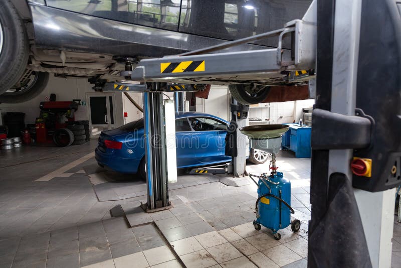 Car raised on a lift for repairing the chassis and engine in a vehicle repair shop. Auto service industry and maintenance stock photos Car raised on a lift for repairing the chassis and engine in a vehicle repair shop. Auto service industry and maintenance stock photos