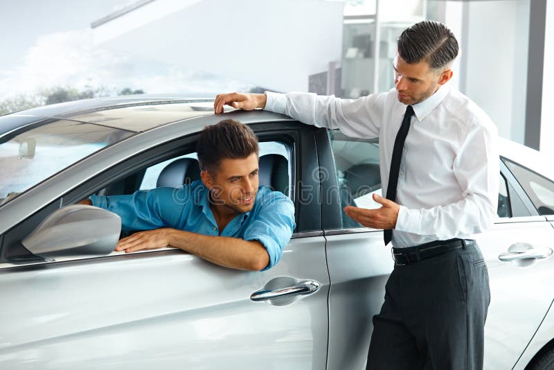 Car Sales Consultant Showing a New Car to a Potential Buyer in S royalty free stock photo Car Sales Consultant Showing a New Car to a Potential Buyer in S royalty free stock photo