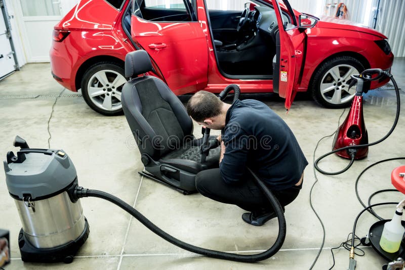 Car Service Worker Cleaning Car Seat with Vacuum Cleaner. Stock Photo